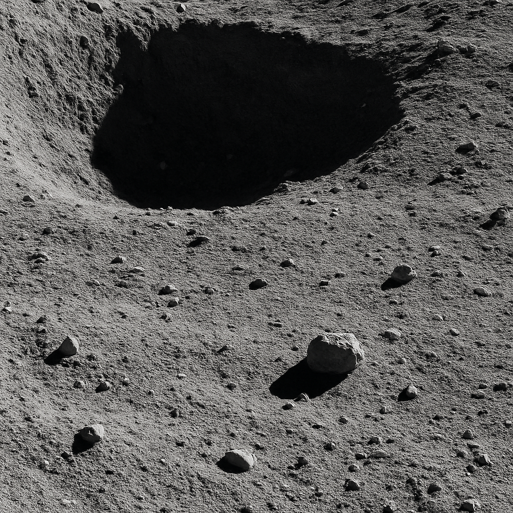 Nahaufnahme der Mondoberfläche: Kraterwand, feinstrukturierter Regolith und kleine Gesteinsbrocken